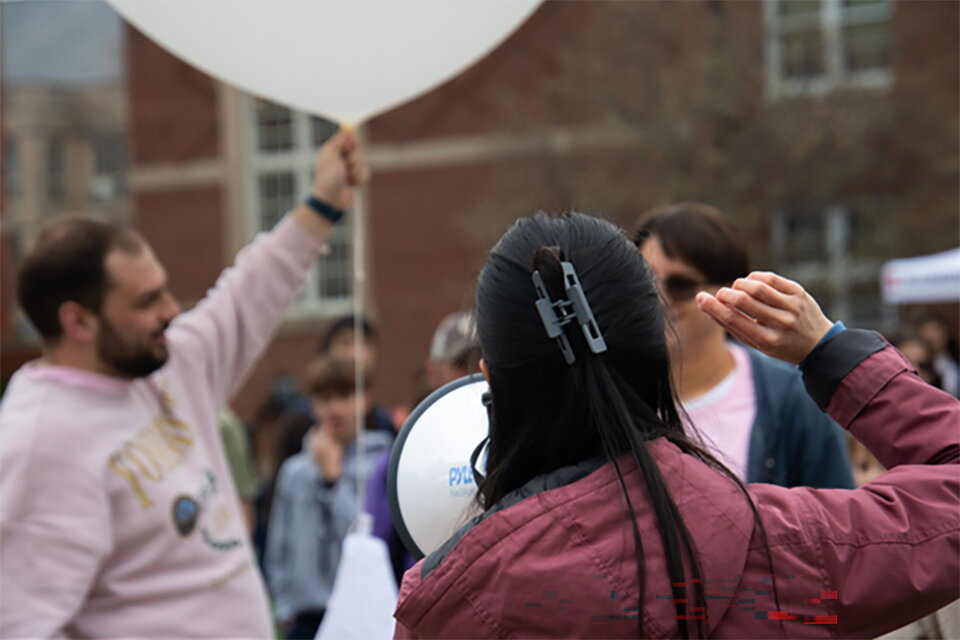 A student holding a weather balloon while another one talks into a megaphone