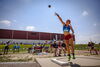 A woman throwing a shotput as other people watch from behind.